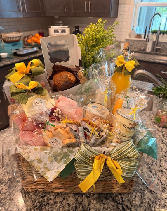 Open handcrafted breakfast basket with pastries, juice, treats, and yellow and green details